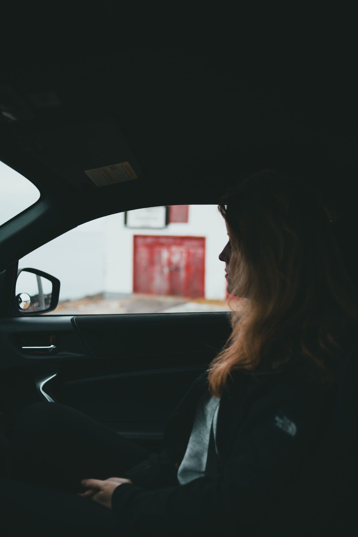 A rider sitting in the passenger seat of a car on an overcast day